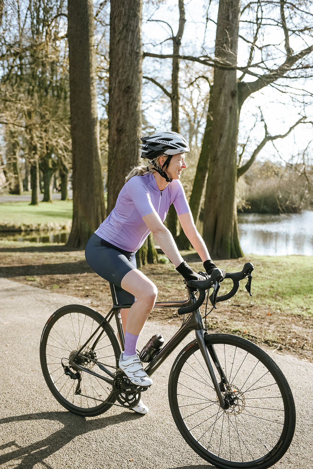 dame op wielrenfiets in korte mouwen lila shirt, donker korte blauwe broek en lila sokken
