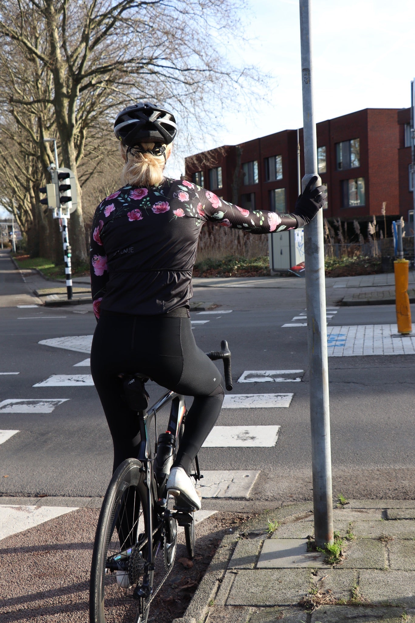 Wielrenster in wielrenkleding met lange wielrenbroek en wielrensport met lange mouwen en roosjes