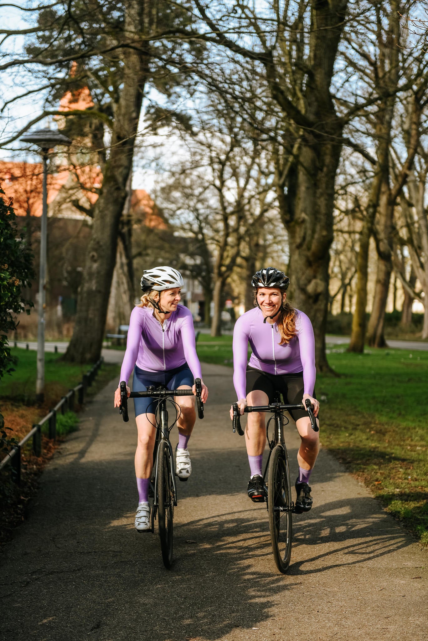 Twee wielrensters met een zwarte en blauwe wielrenbroek van TENUE des Femmes en beide hebben een lange mouwen fiets shirt aan van het design Summer Lila.